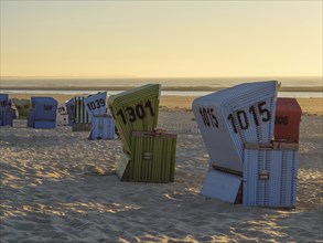 Colourful beach chairs at sunset, sea in the background, sunset on a quiet beach with many