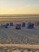 Beach chairs on the beach at sunset and calm sea, bright golden hour and peaceful atmosphere,