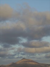 Tranquil mountain under a cloudy sky during sunset, barren landscape of lava mountains, lanzarote,