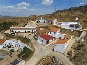 Aerial view of a hilltop village with white houses and orange-coloured roofs, aerial view, cave