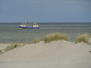 A fishing boat on the sea, surrounded by dunes and sand under a cloudy sky, dunes on an island with