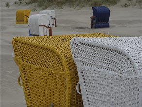Close-up of yellow and white beach chairs on a sandy beach in cloudy weather, colourful beach