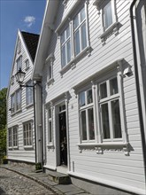 White wooden houses along a cobblestone street, sunny day with historical flair, white wooden