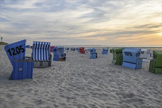 Beach chairs on a sandy beach with a view of the sea at sunset, many colourful beach chairs on a