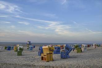 Many colourful beach chairs on a sandy beach with blue sky and sea in the background, many
