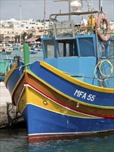 Two colourful fishing boats in the harbour off a coastal town in sunny weather with blue sky, many