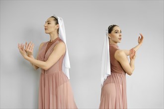 Two ballerinas standing on grey background and perform hand and palms movements