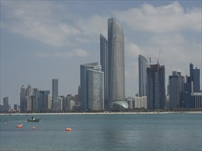Modern skyscrapers of a city on the seashore under a slightly cloudy sky, impressive skyline of a