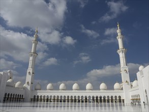 Large mosque with two high minarets and numerous white domes under a blue sky, beautiful mosque