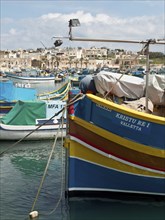 Colourful fishing boats with nets in the harbour, the city is visible in the background, many