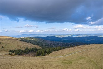 Cloudy sky over a quiet mountain landscape with a path leading into the valley, Feldberg, Germany,