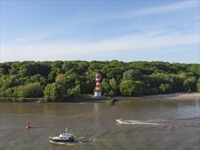 A boat sailing on a river, with a red and white lighthouse and a forest in the background, green