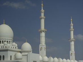 Majestic mosque with white domes and minarets under a clear blue sky, large mosque with white domes