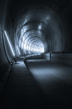 An empty tunnel with cold metallic walls and artificial lighting that creates a futuristic
