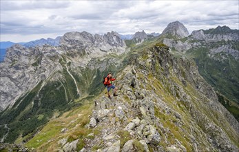 Mountaineer on a narrow rocky mountain path on a ridge, descent from the Raudenspitze, view into