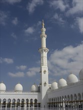 Elegant mosque with high minarets, white domes and golden decorations under a blue sky, beautiful