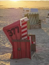 Red and white beach chair on a sandy beach at sunset, sunset on a quiet beach with many colourful