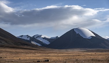 Autumnal plateau with brown grass, glaciated and snow-covered peaks, Ak Shyrak Mountains, near the