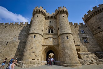 Super wide angle shot, group of visitors approaching the entrance of a large castle with two round