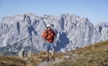 Mountaineer on hiking trail in front of rocky mountain peaks, behind Sesto Dolomites, Carnic Main