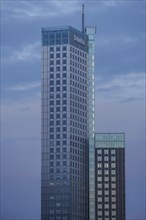 A modern skyscraper with a glass facade against a blue sky, skyline of a modern city on a river