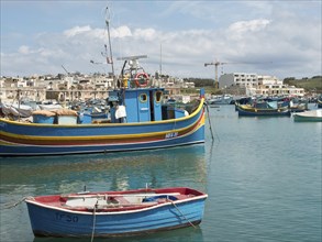 Harbour view with fishing boats and town in the background, a crane is visible, many colourful