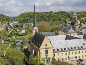 Panorama of a city with a central church and a river, surrounded by historical buildings and green