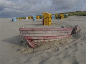 An old boat is buried in the sand, surrounded by colourful beach chairs and cloudy sky, colourful