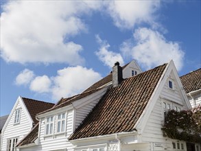 White wooden houses with red tiled roofs and flowering plants against a clear sky, white wooden