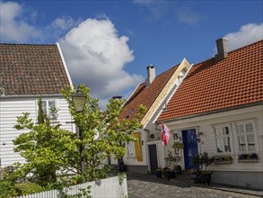 White houses with tiled roofs, lantern, and fence at cobblestone street and blue sky, white wooden