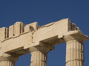 Close-up of ancient marble columns of a ruin in front of a clear blue sky, historical columns and