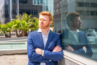 Proud and pensive businessman standing next to the glass facade of a financial building