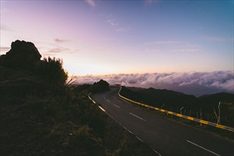 Empty mountain road leading into the clouds at dusk, creating a tranquil atmosphere. Madeira,