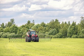 Tractor fertilizing a green field in the countryside