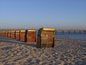 Beach chairs in rows on the sun-drenched beach with a view of the sea and the pier, beach chairs in