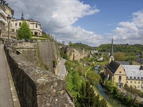 View of an old town with imposing fortress wall, church and river, surrounded by historic buildings