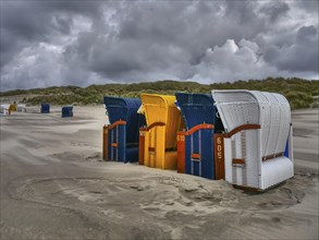 A group of colourful beach chairs on the coast in unstable weather, colourful beach chairs on the