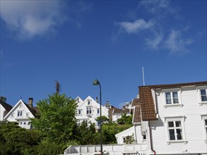 White houses with red roofs in a hilly landscape under a blue sky with clouds, white wooden houses