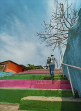 Man climbing multicolored steps. Rear view of a person climbing stairs, Nagarote