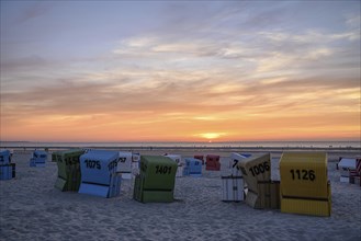 Beach chairs in different colours at sunset on the beach, many colourful beach chairs on a warm