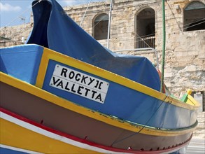 Side view of a colourful boat with cover and the inscription ROCKY II VALLETTA, many colourful