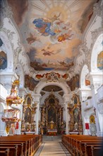 Interior of a baroque church with an elaborate ceiling fresco and a magnificent gilded altar,