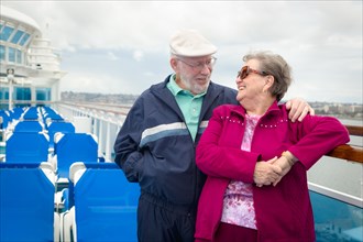 Senior adult couple enjoying the view from their passenger cruise ship railing