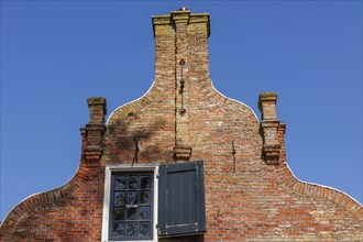 A historic brick house with an open window and tiled roof under a blue sky, historic houses and a
