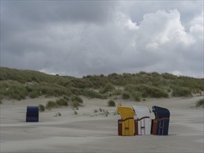 Scattered beach chairs and grey sky over a deserted beach, colourful beach chairs on the beach and