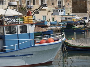 Boats in the harbour of a coastal town with bright colours and adjacent buildings in sunny weather,