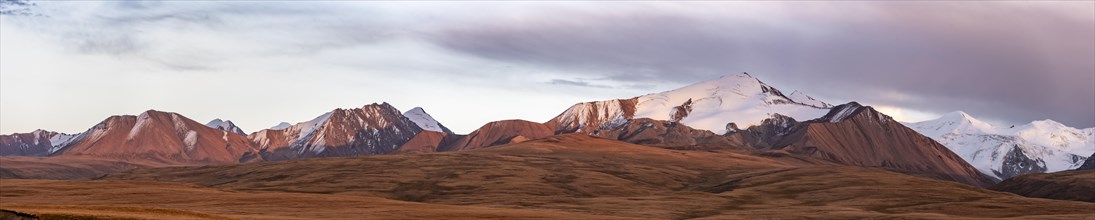 Glaciated and snow-capped mountains, dramatic mountain landscape at sunrise, autumnal plateau with