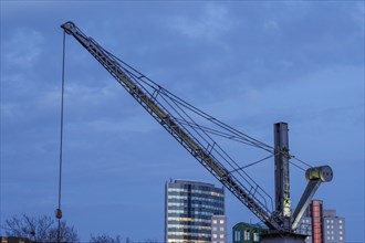 Large crane in front of a modern building under a blue sky in the city, small harbour in a big city