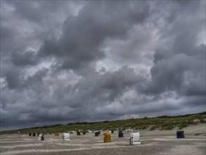 Dark clouds towering over a grey beach with scattered beach chairs, colourful beach chairs on the