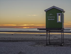 Sunset on the beach with a green beach hut and soft colours, beautiful sunset on the beach of an